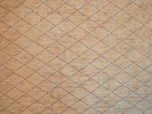 Warm oat-beige chenille with charcoal diamond lattice and tiny muted red woven accents