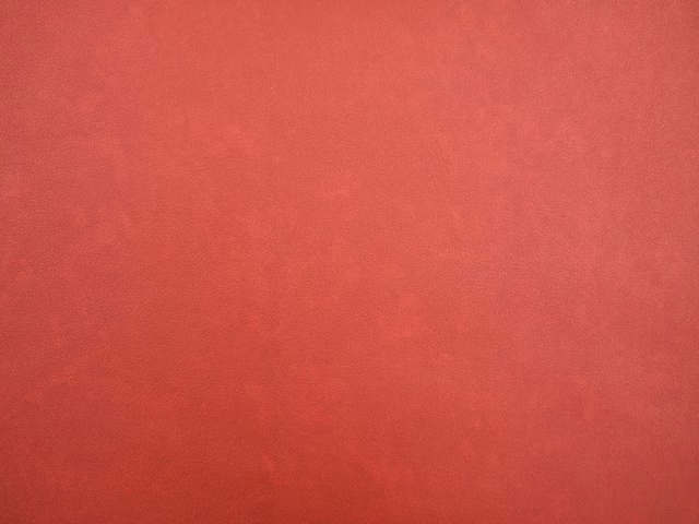 Mottled crimson-red faux leather surface with subtle darker tonal shading