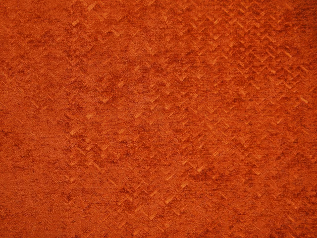 Close-up of burnt-orange chenille with softly mottled, brushed texture and darker strokes