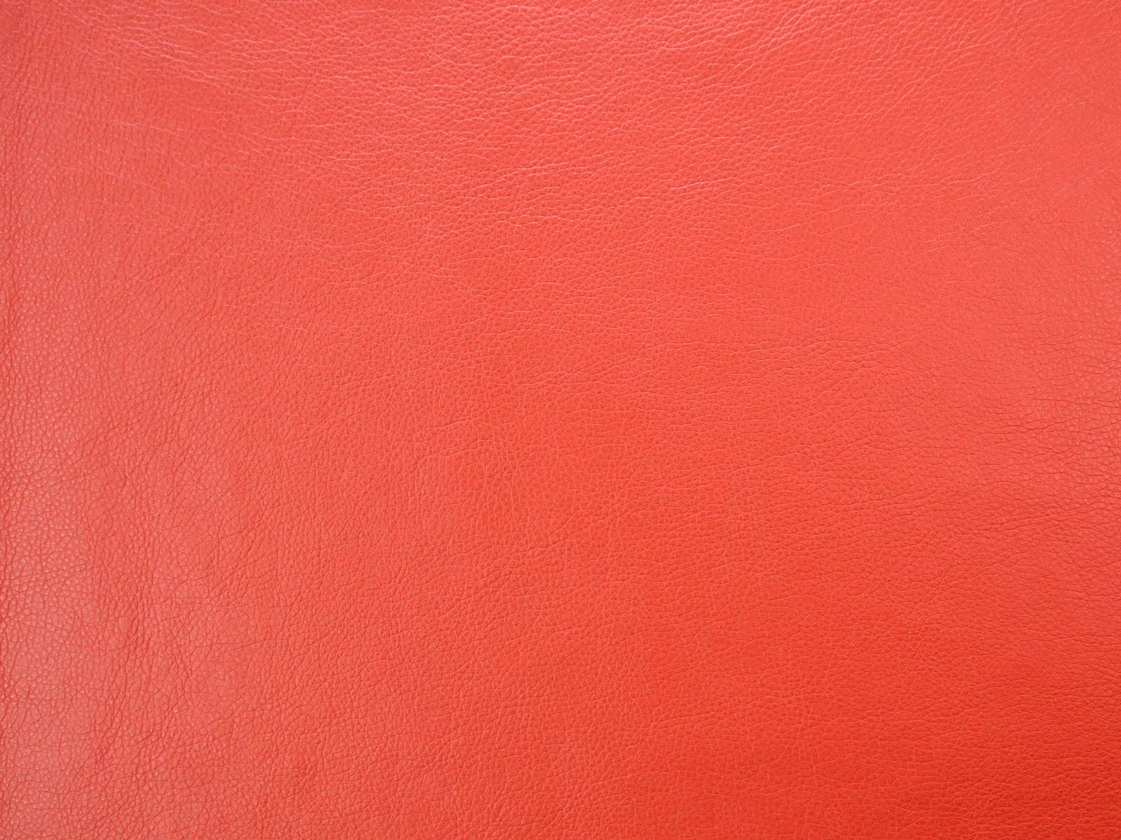 Vivid coral-red faux leather with a fine pebbled grain and subtle sheen