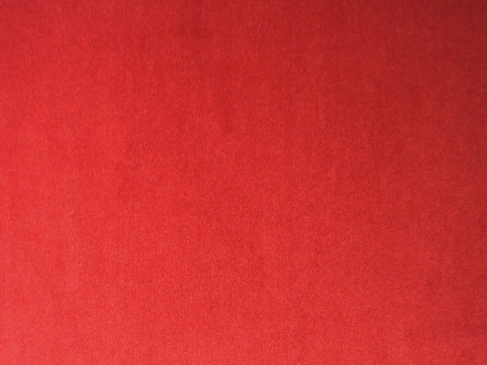 Deep crimson-red plain velvet showing soft directional nap and subtle tonal shading