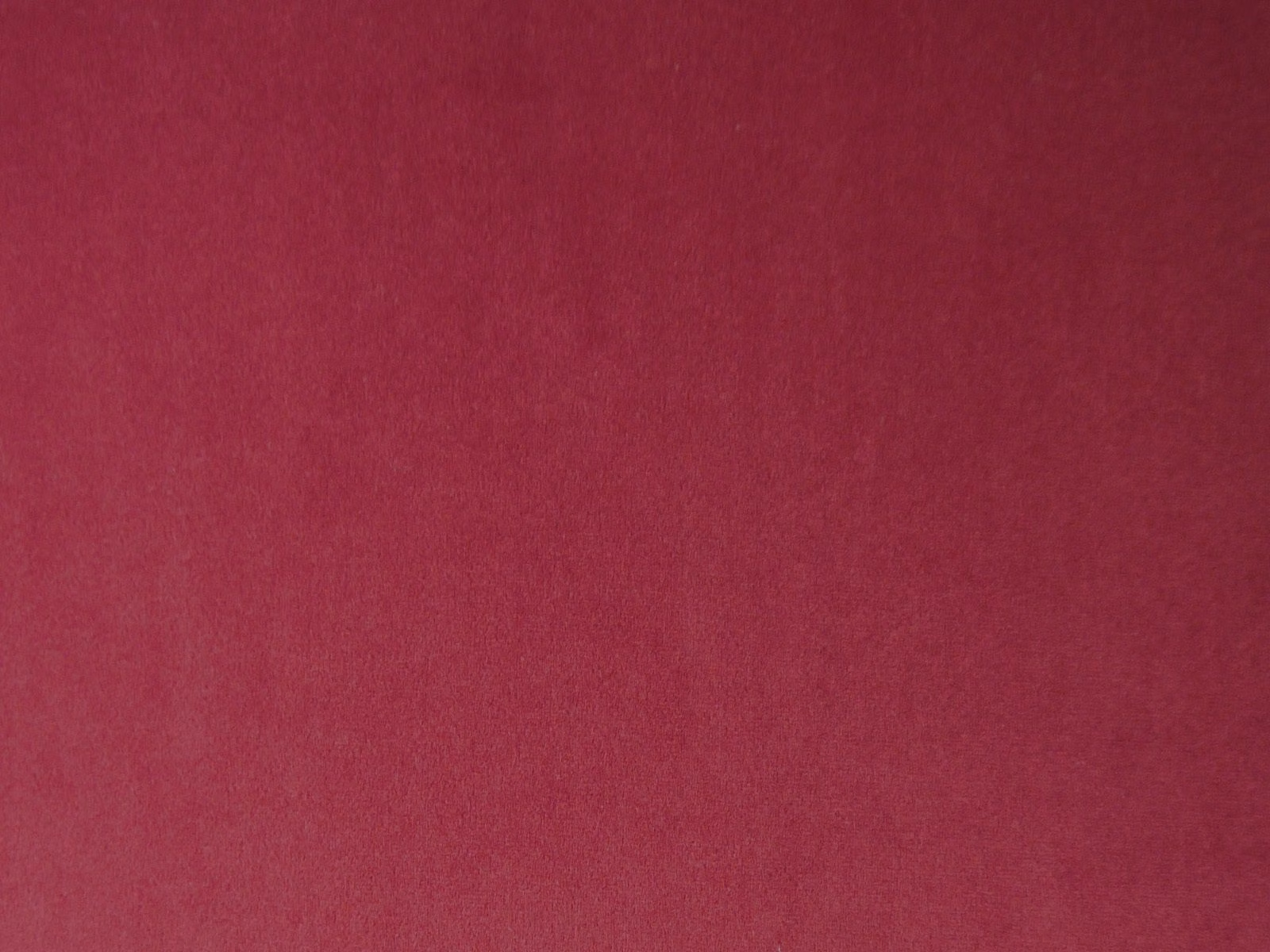 Deep raspberry-red plain velvet showing a soft directional pile and subtle tonal shading