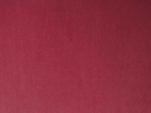 Deep raspberry-red plain velvet showing a soft directional pile and subtle tonal shading
