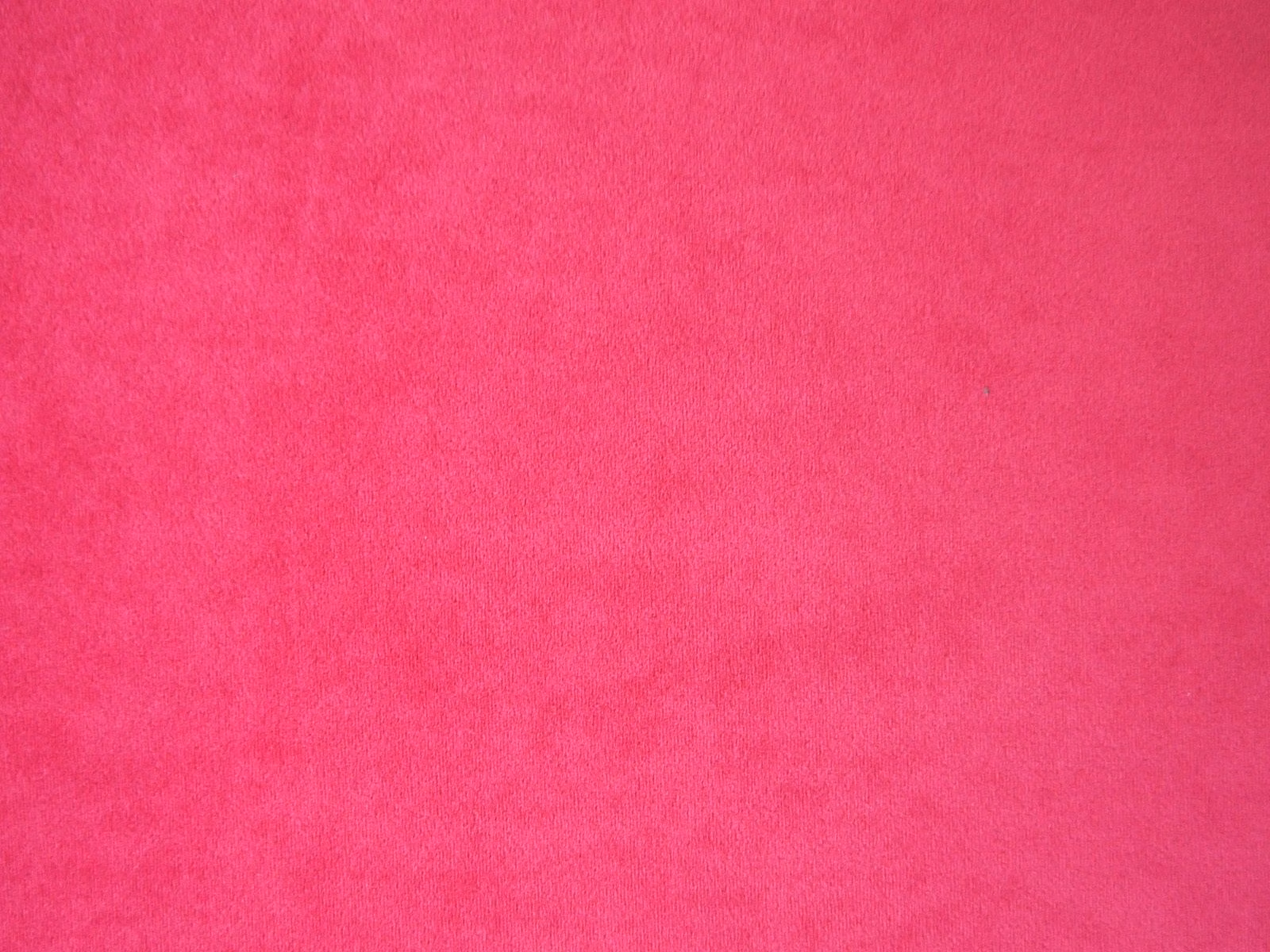 Vivid fuchsia pink velvet swatch showing a soft, subtly directional plush pile