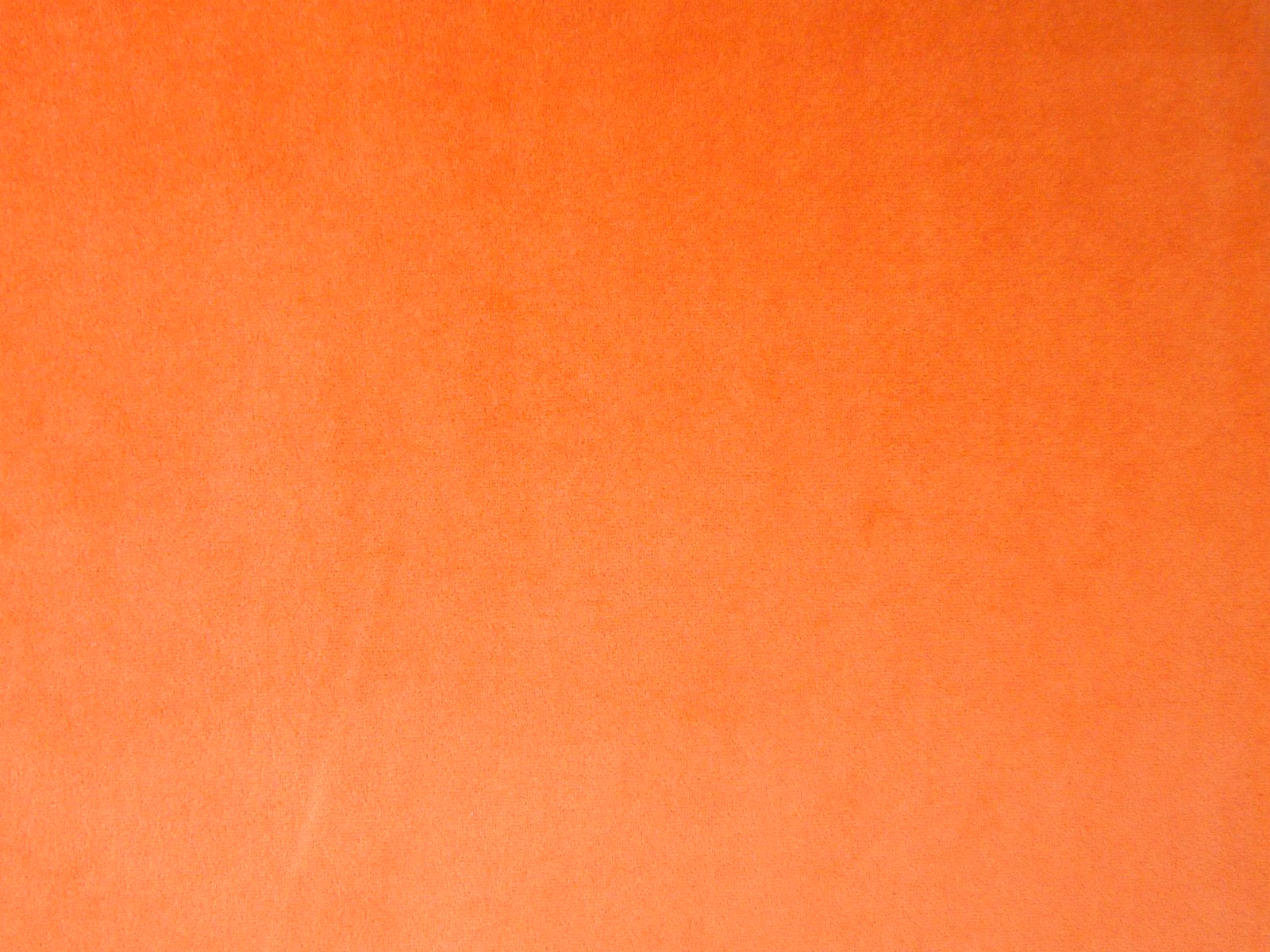 Close-up of vivid burnt-orange plain velvet with soft directional nap shading
