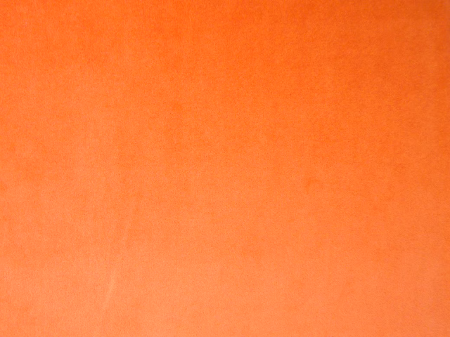 Close-up of vivid burnt-orange plain velvet with soft directional nap shading