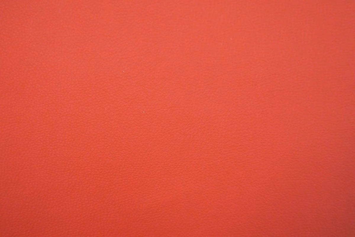 Close-up of warm coral-red faux leather with a fine, subtly textured grain