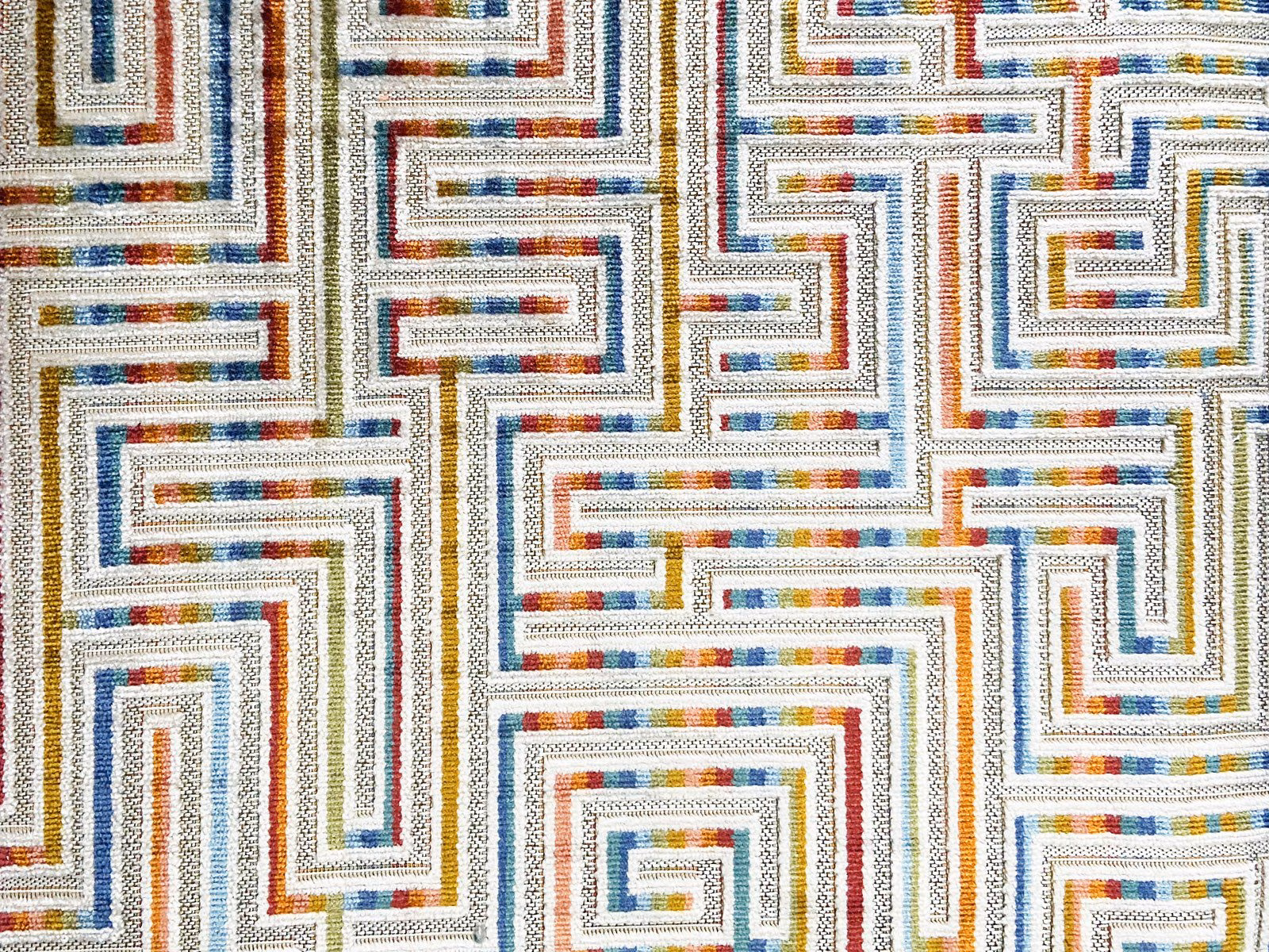 Ivory velvet with blue, rust and ochre maze lines in a textured close-up