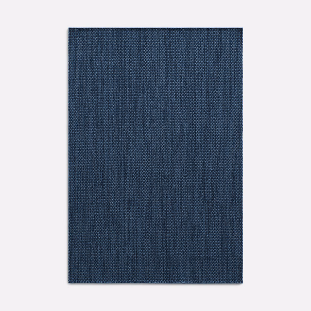 Deep indigo woven curtain fabric with fine vertical striations and subtle tonal texture