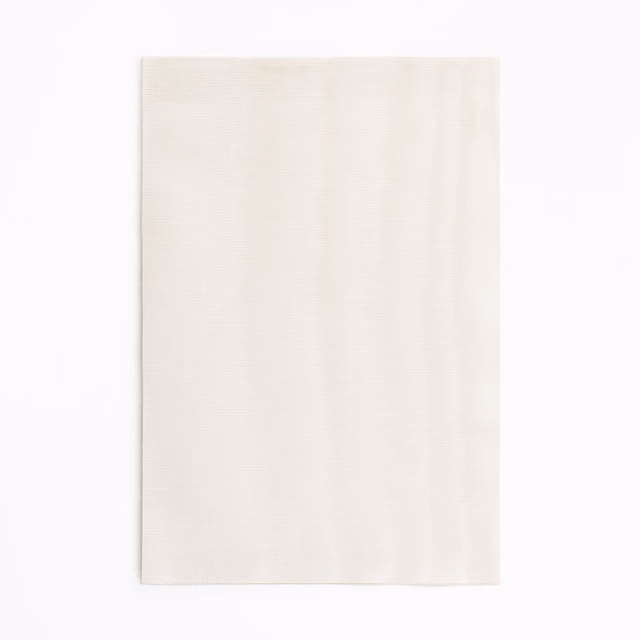 Pale powder-ivory curtain fabric with subtle vertical tonal movement and soft sheen