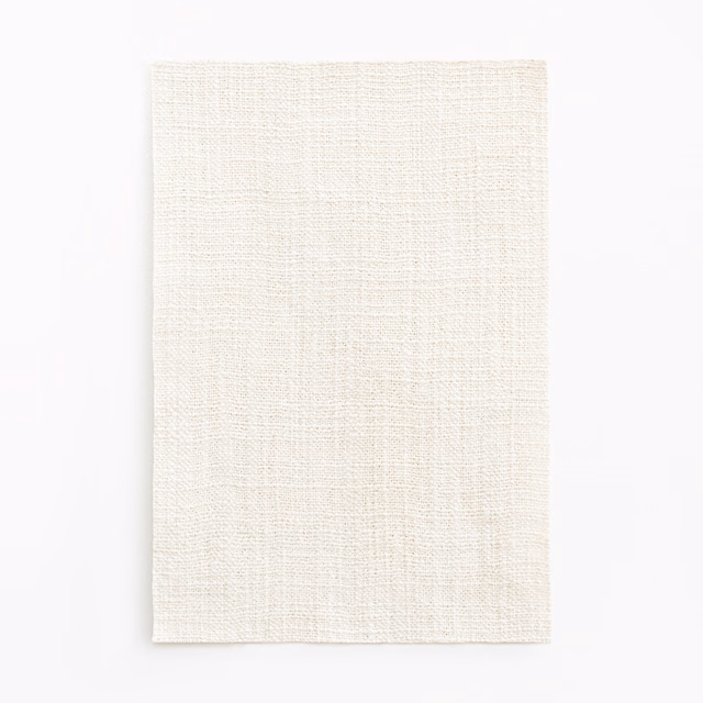 Pale ivory woven textile with fine slub texture and softly varied surface
