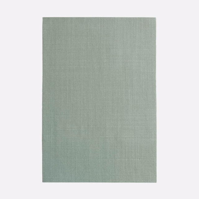 Pale sage-green plain fabric with fine vertical weave and softly mottled texture