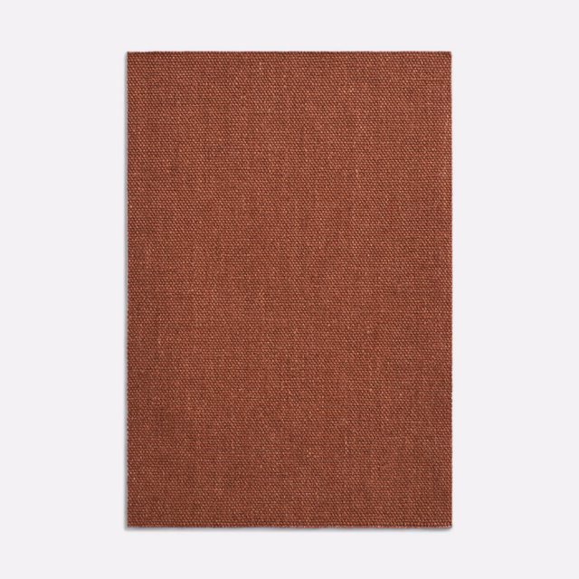 Close-up of rust terracotta fabric with a fine, subtly mottled plain weave
