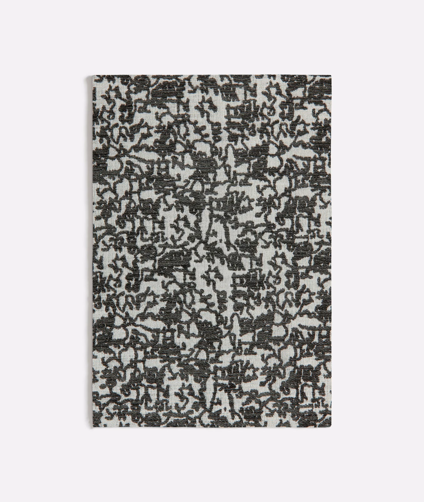 Charcoal black botanical tracery woven across a pale grey textured ground