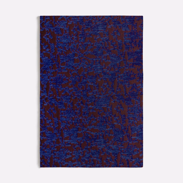 Deep blue-purple woven textile with burgundy organic marks and tactile irregular texture