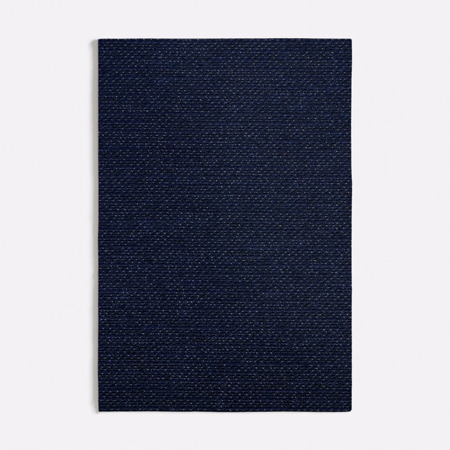 Close view of dense midnight-blue weave with fine lighter flecks across the surface