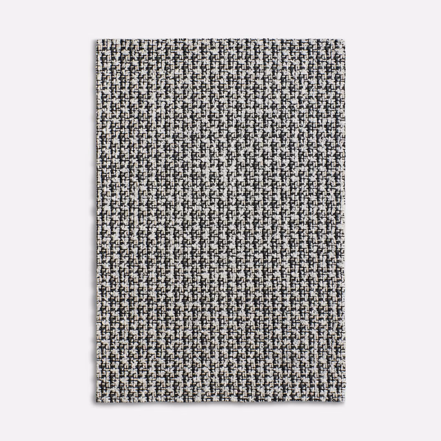 Close view of Carillon Black’s black-and-ivory flecked woven textile with vertical texture.