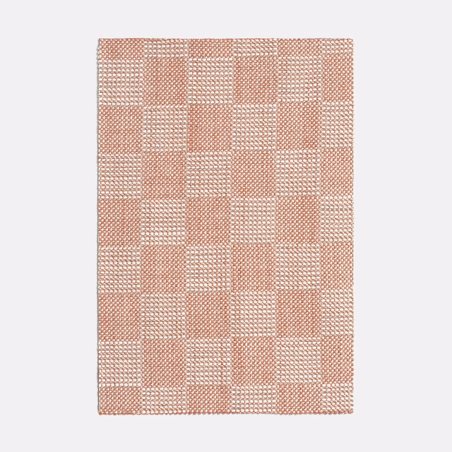 Muted terracotta and cream checked textile with a tactile woven surface
