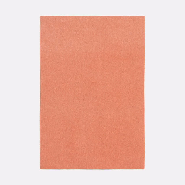 Close view of a plain coral-pink woven textile with a soft, even surface