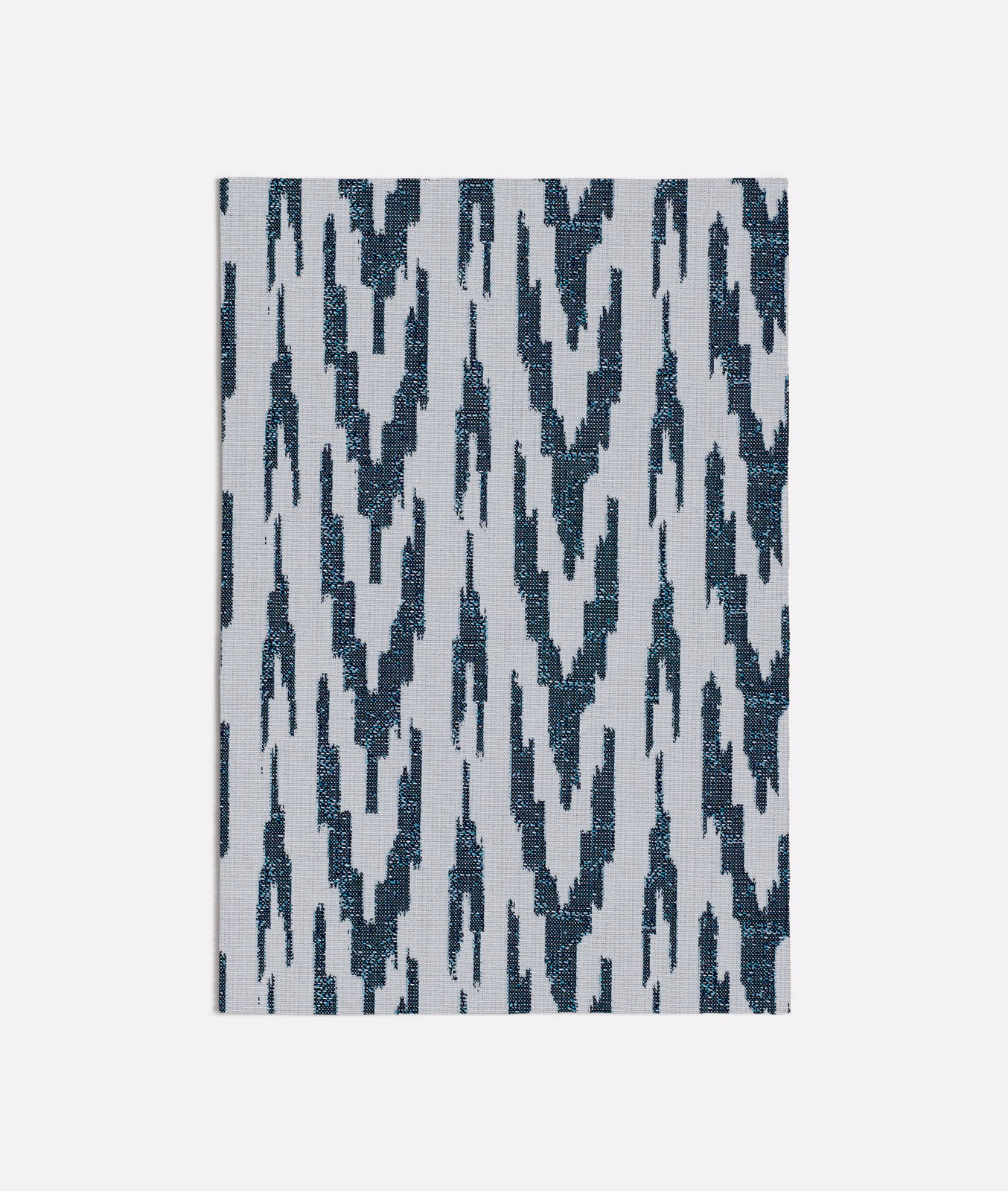 Deep blue broken ikat marks on a pale grey textured woven fabric