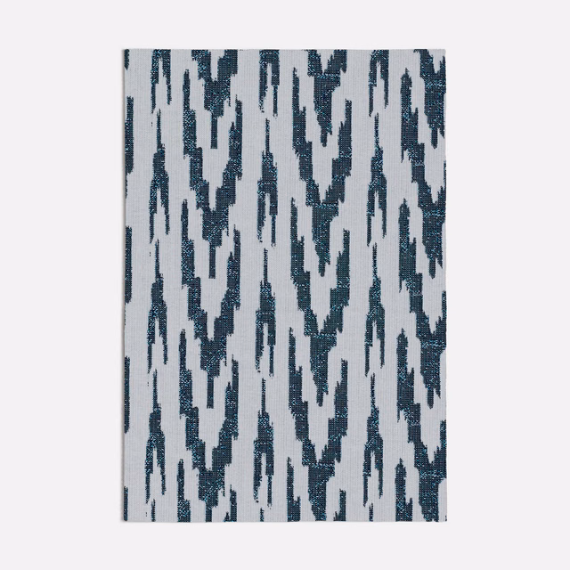 Deep blue broken ikat marks on a pale grey textured woven fabric