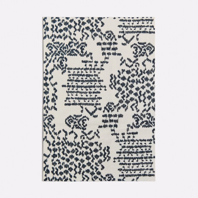 Ink-blue distressed botanical and geometric motifs scattered across a cream woven ground