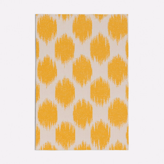 Saffron-yellow ikat-style motifs on a textured ivory woven ground