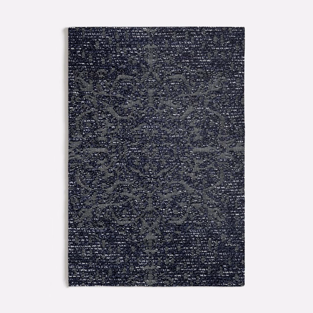 Dense blue-grey weave with shadowed medallions and flecked surface texture