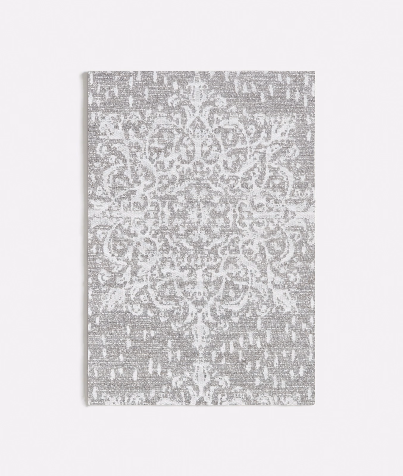 Cool grey textile with white scrolling medallion, mottled ground, and distressed flecks