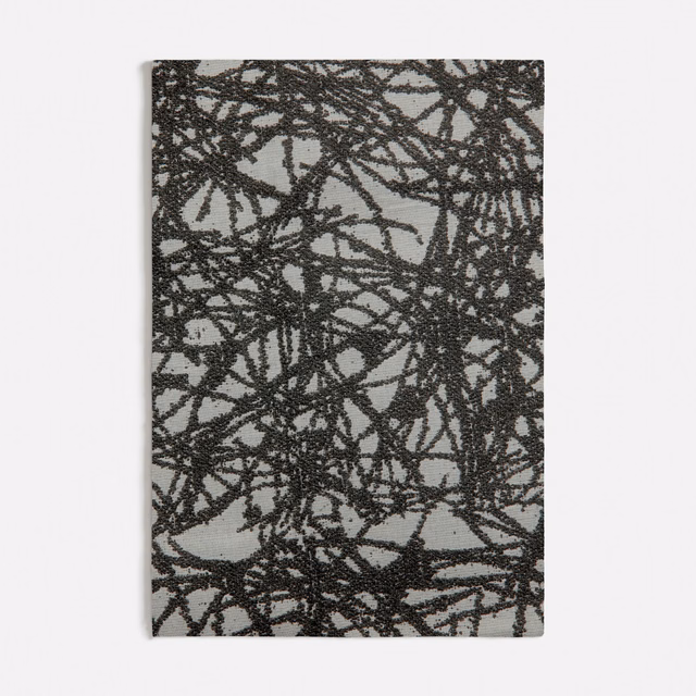 Charcoal-grey textile with dense black scribble lines and raised texture
