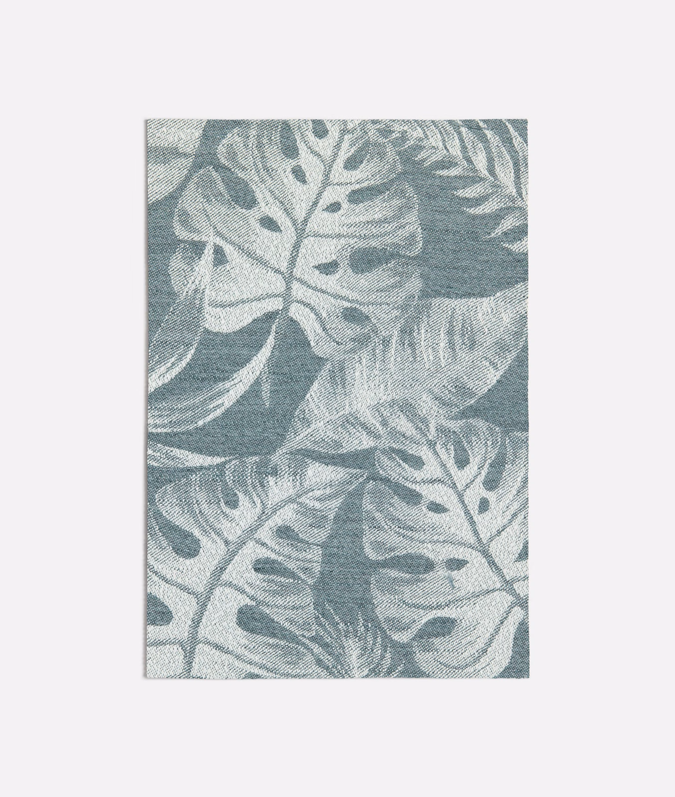 Dark seafoam woven fabric with pale oversized tropical leaves and tactile texture