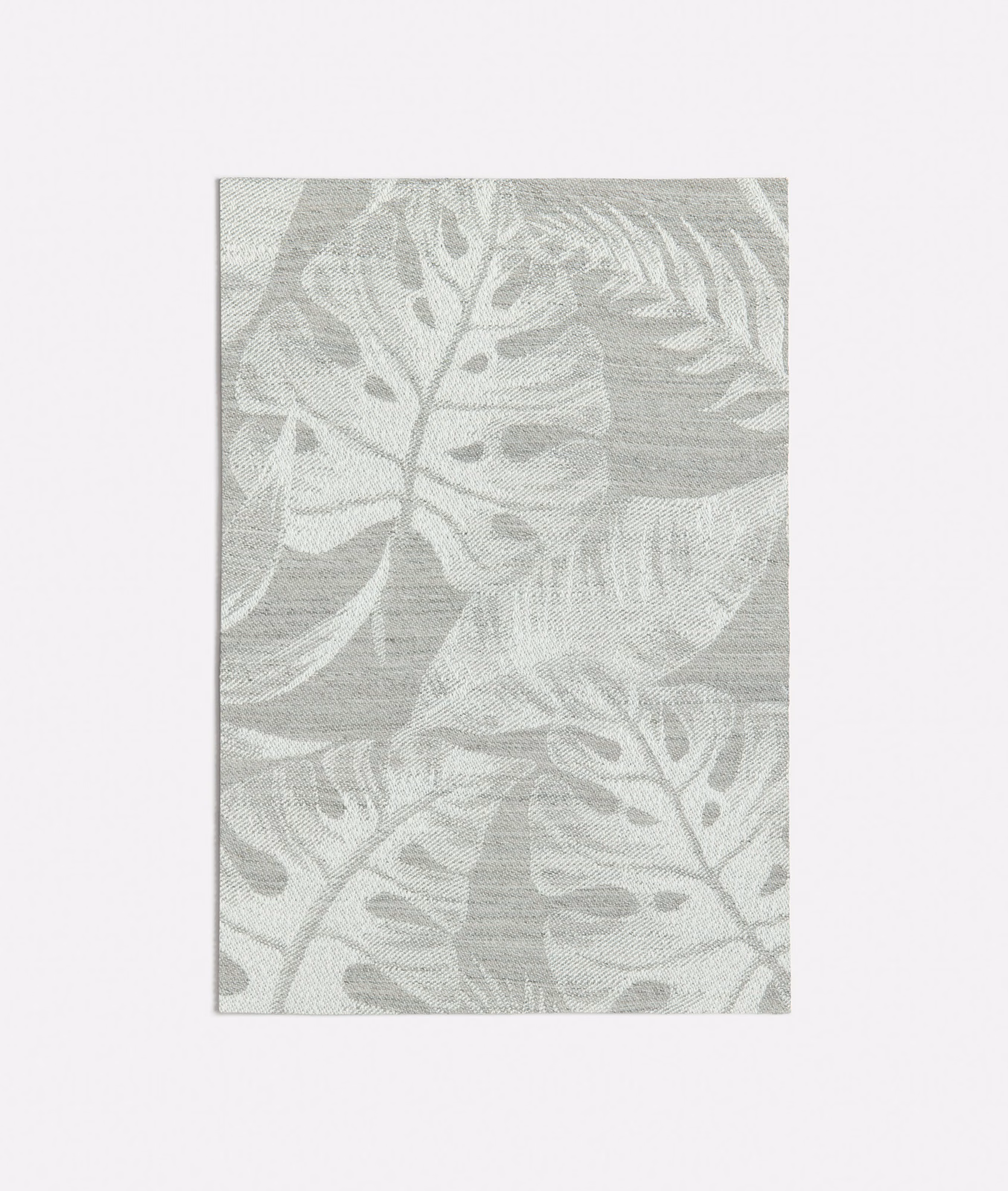 Pale grey woven fabric with oversized botanical leaves and softly layered tonal texture