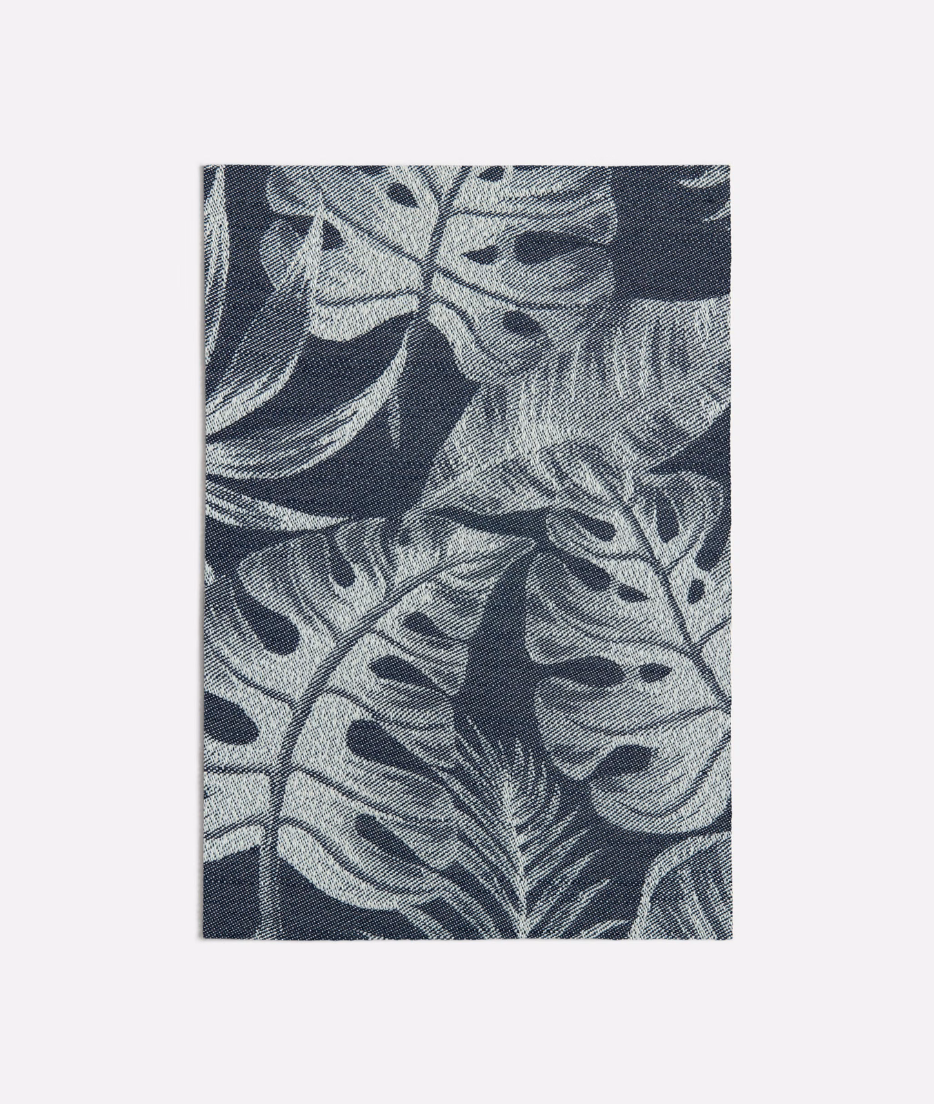 Deep navy woven ground with oversized blue-grey tropical leaves and fine texture