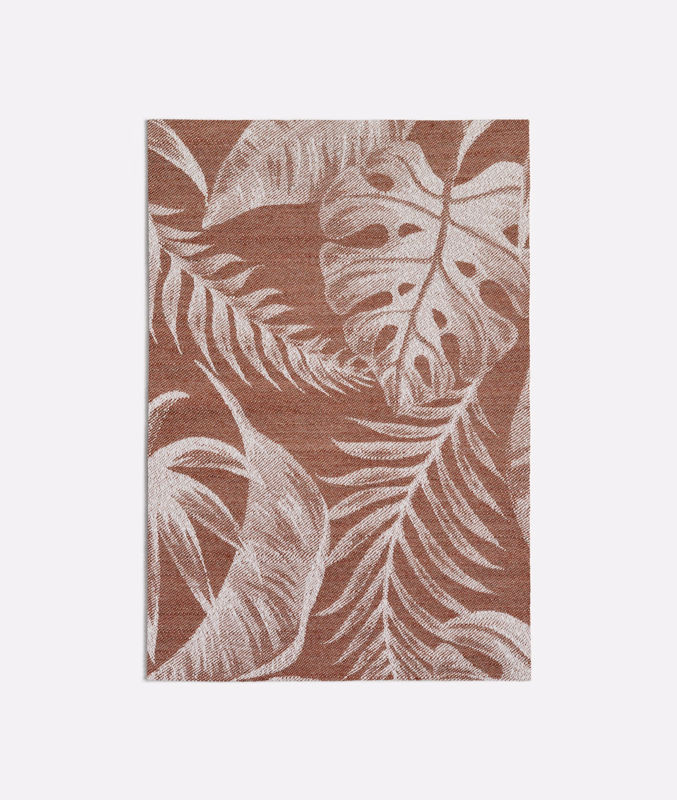 Muted terracotta woven ground with oversized cream tropical leaves and fronds