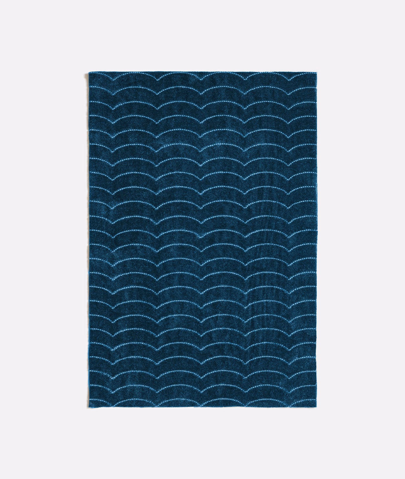 Dark indigo textile with repeated pale blue scallop lines and subtle woven texture