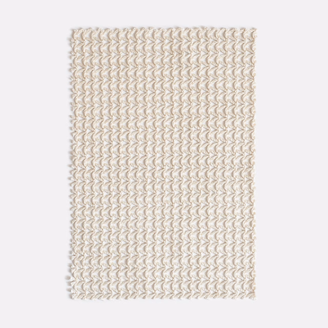 Warm ivory outdoor textile with rows of raised, looping corded motifs
