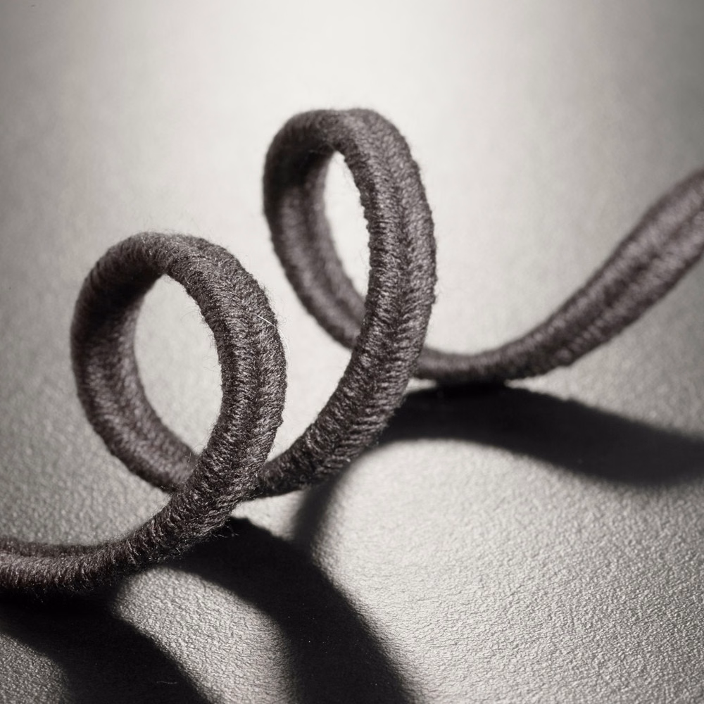 Deep black raised soutache loops casting shadows across a textured dark ground
