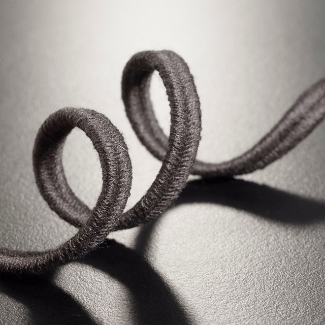 Deep black raised soutache loops casting shadows across a textured dark ground