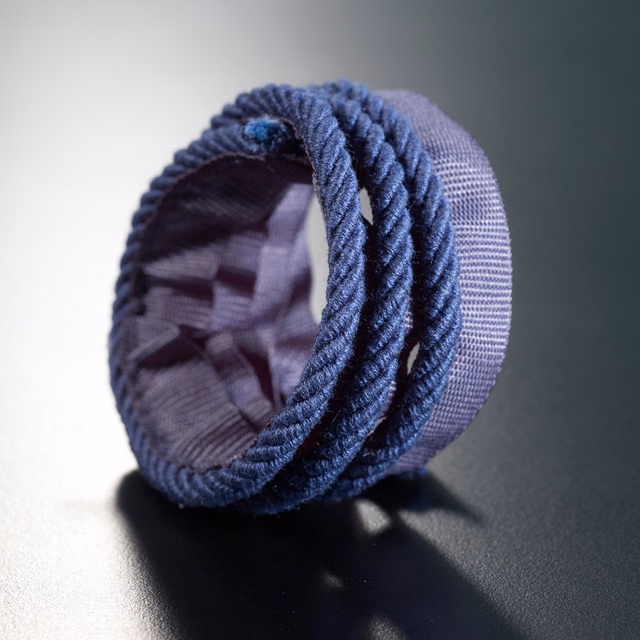 Deep navy woven lipcord with raised twisted edging, rolled to show its texture