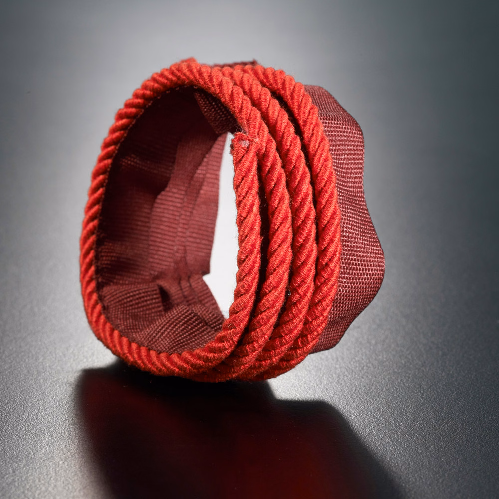 Saturated rosso red twisted lipcord wrapped around a textured woven fabric backing
