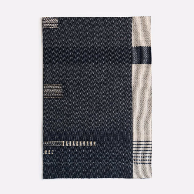 Charcoal-navy jacquard swatch with ivory blocks, slim bars and a finely woven surface