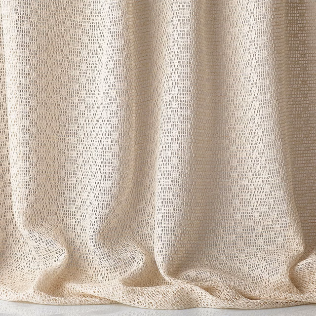 Warm ivory jacquard with open geometric weave gathered into soft curtain folds