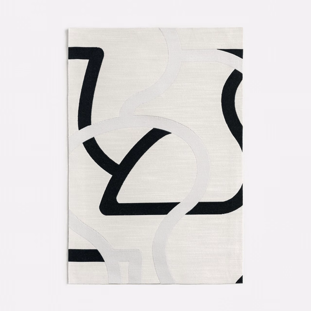 Ivory jacquard swatch with bold black loops and pale grey sweeping arcs