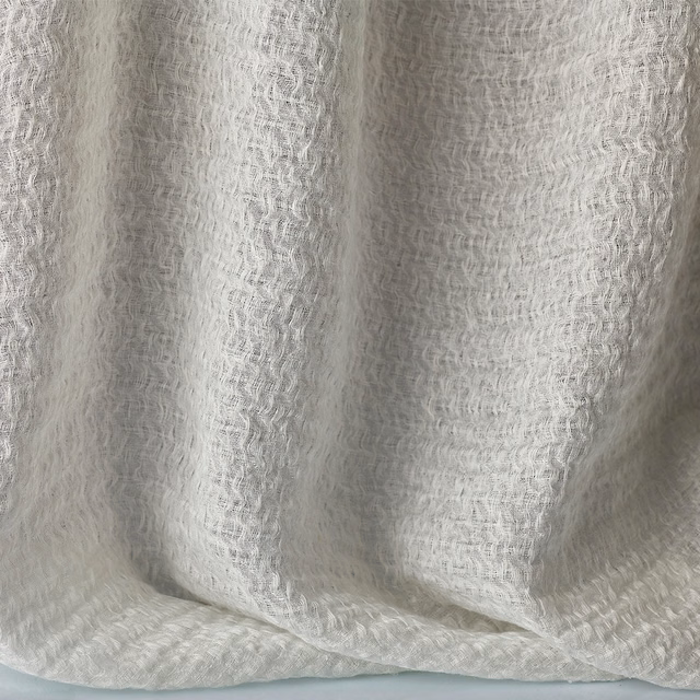 Soft warm-white jacquard with rippled woven texture falling in loose curtain folds