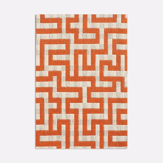 Warm brick-red angular maze pattern woven across a cream jacquard ground