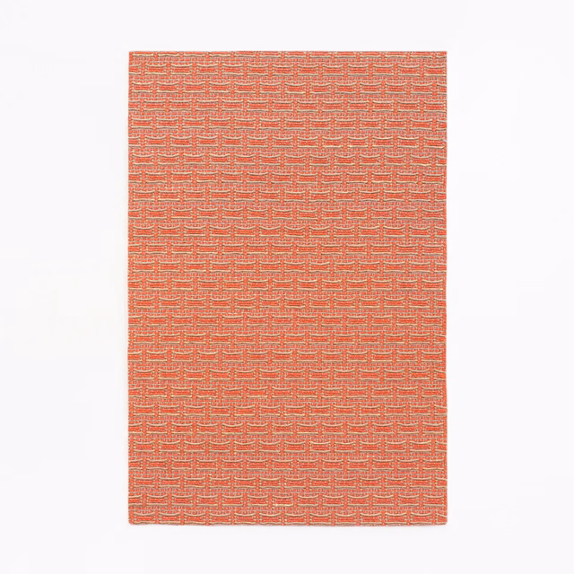 Coral-red jacquard swatch with a tightly repeated stepped geometric weave