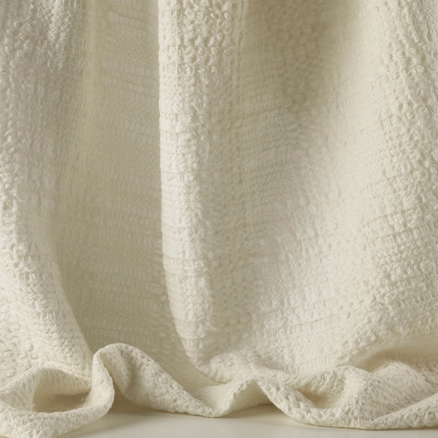 Warm ivory jacquard with raised motifs and softly draped, tactile folds