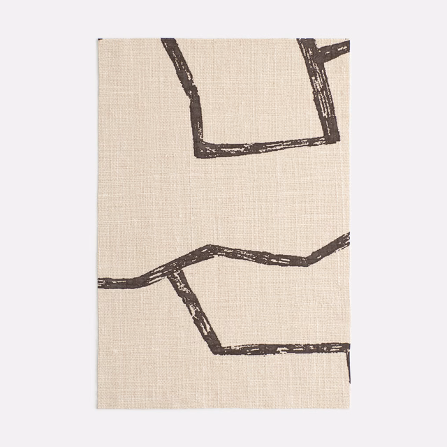Warm beige fabric with distressed dark brown geometric outline motifs and visible woven texture