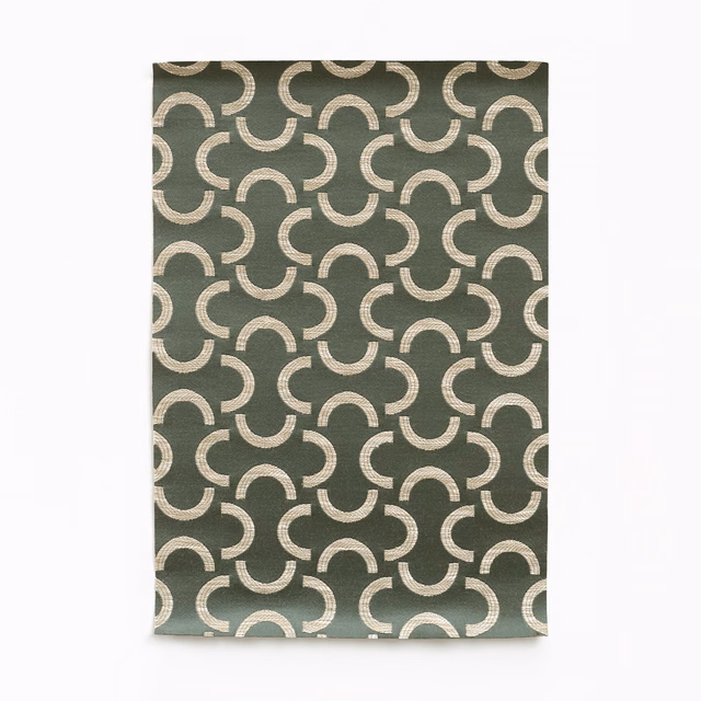 Muted olive-green woven fabric with pale interlocking crescent motifs