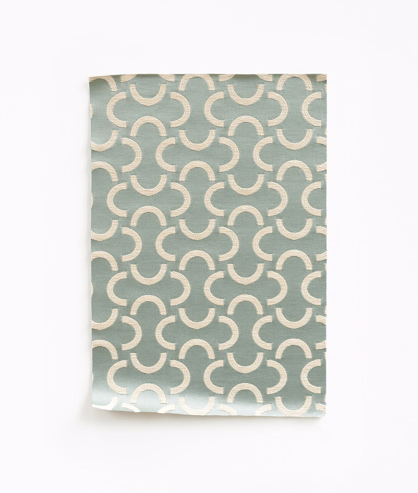 Muted sage-green satin swatch with repeating ivory curved motifs and subtle sheen